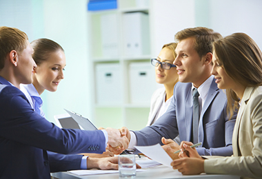 Image of confident businessmen handshaking at meeting